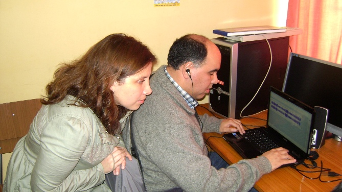 Karina Riquelme observa como Jorge Oyarzo trabaja en un computador.