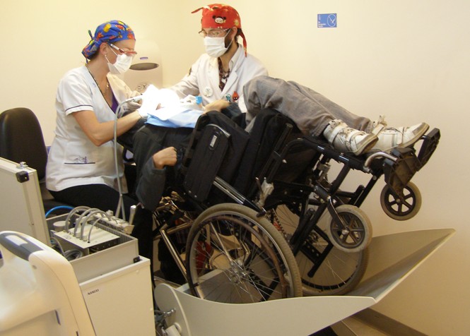Médicos de la Clínica de Cuidados Especiales en Odontología atendidendo a uno de los pacientes en silla de ruedas utilizando el nuevo reclinador. 