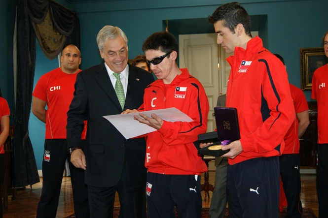 El Presidente Sebastián Piñera entrega el diploma en Braille a Cristián Valenzuela, les acompaña Christopher Guajardo. 