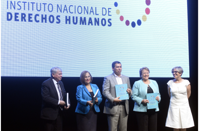 Fotografía de Presidenta Bachelet recibiendo el informe de manos de Lorena Fries. 