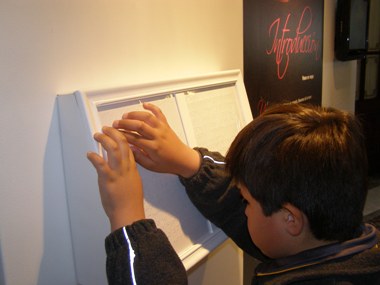 Alumno del Colegio Santa Lucía, lee en Braille información que exhibe Biblioteca Nacional.