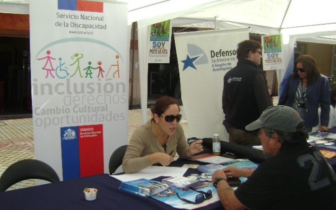 La profesional Jocelyn Franco en el stand Senadis atendiendo a una persona.