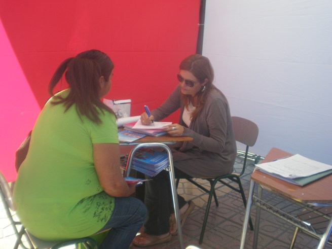 La profesional Ximena Arancibia en el stand Senadis atendiendo a una persona.