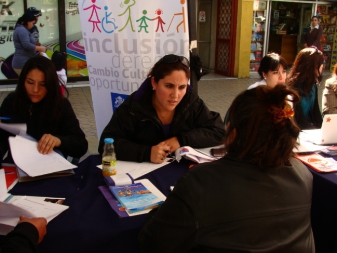 La profesional de la Dirección Regional del Senadis Antofagasta en el stand del servicio entregando información.