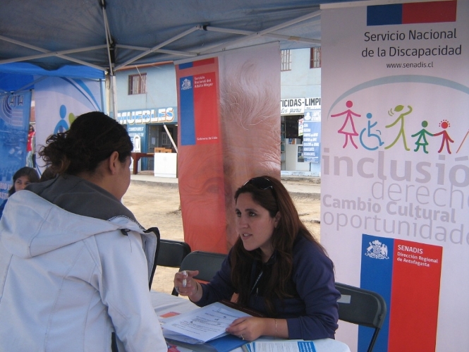 La profesional del Senadis en el stand institucional entregando información.