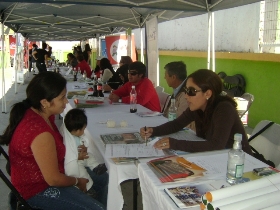 La profesional Jocelyn Franco entregando información a una mujer que está con su hijo.