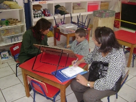 Las profesionales están junto a un niño en la evaluación