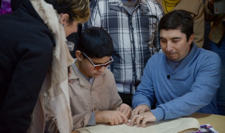 Alumnos ciegos del Instituto Vicente Mosquete explorar el libro creado por la Nasa.
