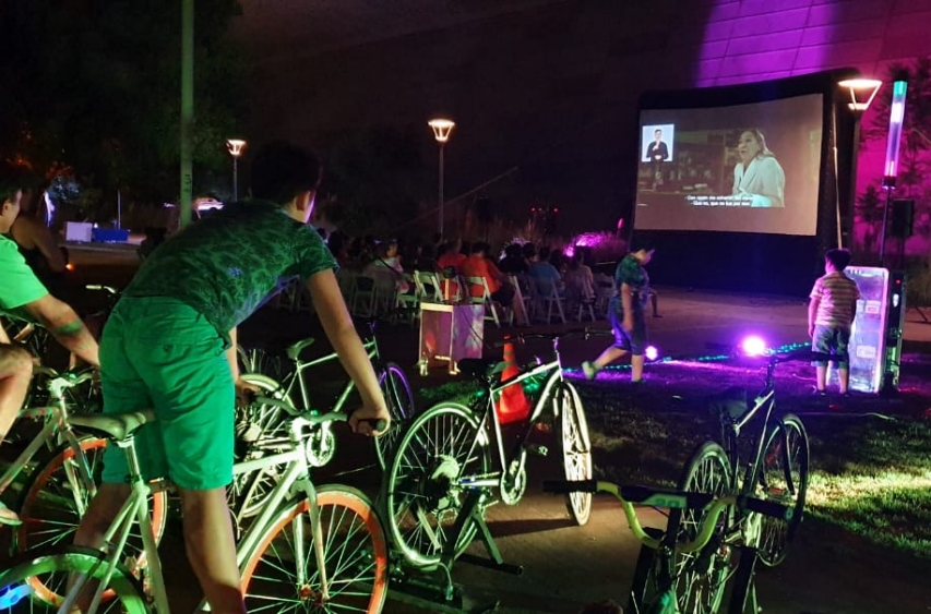 Asistentes pedaleando para dar energía a la proyección de le película. 