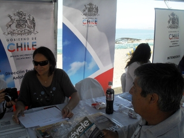 La secretaria del Senadis, Yasna Salvo en el stand informativo entregando información a una persona.