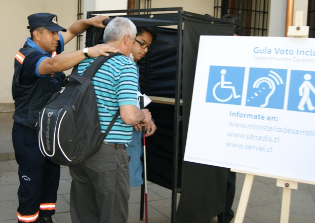 Persona con Discapacidad siendo asistida para votar.